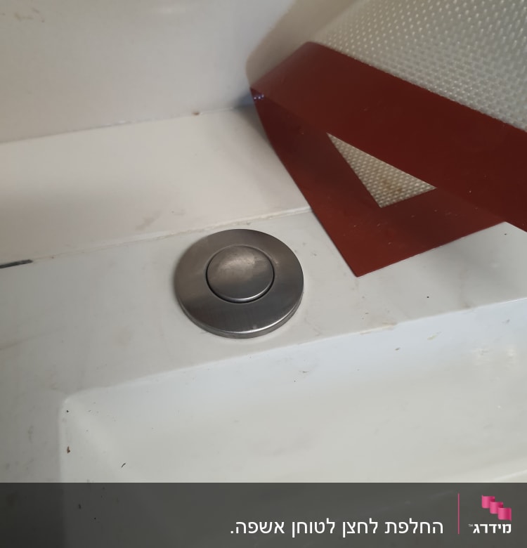 כפתור נירוסטה על משטח כיור לבן